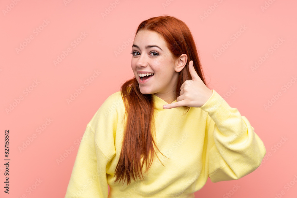 Redhead teenager girl over isolated pink background making phone gesture. Call me back sign Redhead teenager girl over isolated pink background making phone gesture. Call me back sign