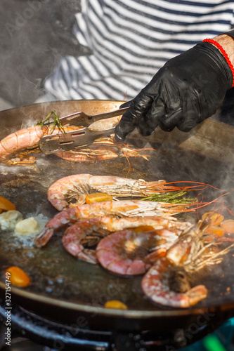 chef cooks shrimp at street food festival photo