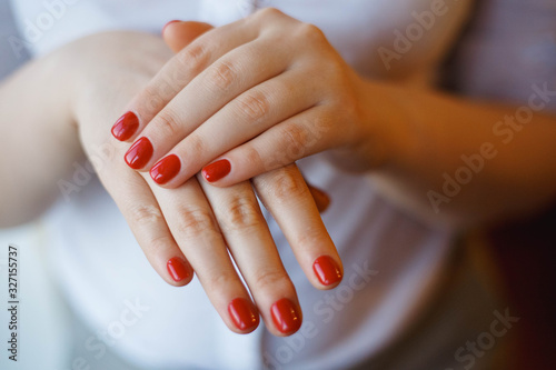 Closeup of hands of a young woman with red manicure on nails.