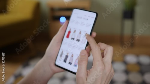 Woman Looks at Goods in Online Store Clothing. Buy Fashion Clothes Directly on Smartphone. Woman at Home Lying on Couch in Living Room Using Smartphone Buys in Internet Shop.