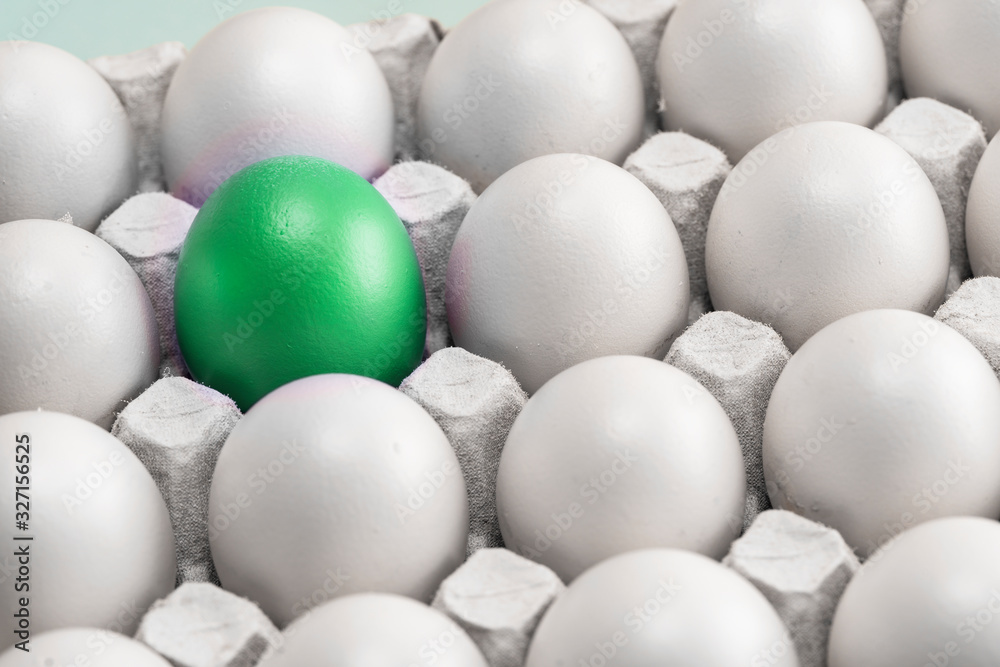 one green egg among many white eggs in the box, close-up. upstart and leader, symbol of individuality. concept for Easter one green egg among many white eggs in the box, close-up. upstart and leader, symbol of individuality. concept for Easter