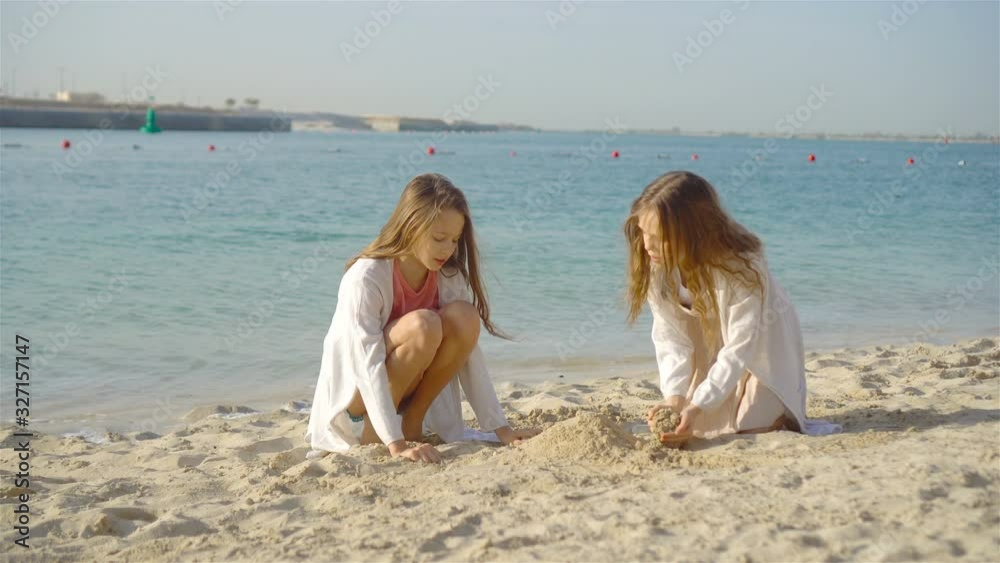 Two little happy girls have a lot of fun at tropical beach playing together Two little happy girls have a lot of fun at tropical beach playing together