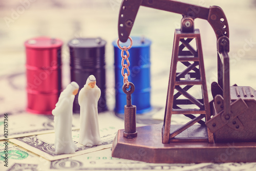 Crude oil price and world petroleum demand concept : Gulf oil owners talk on a spot price and trade deal or buying contract. Oil rig or pumpjack and black drum barrels on US USD dollar currency notes. photo