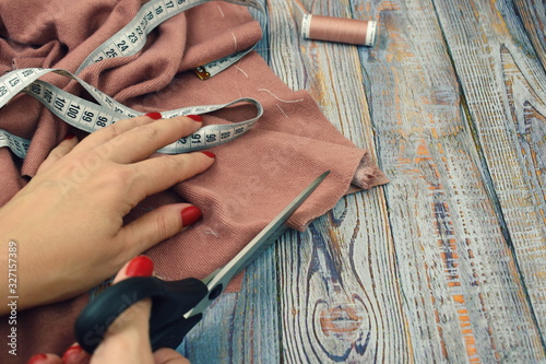 Woman seamstress sews clothes. The fabric on the table. Women's needlework.