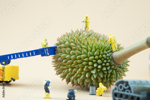 Miniature people chemical team in hazmat yellow suits examining Durian.