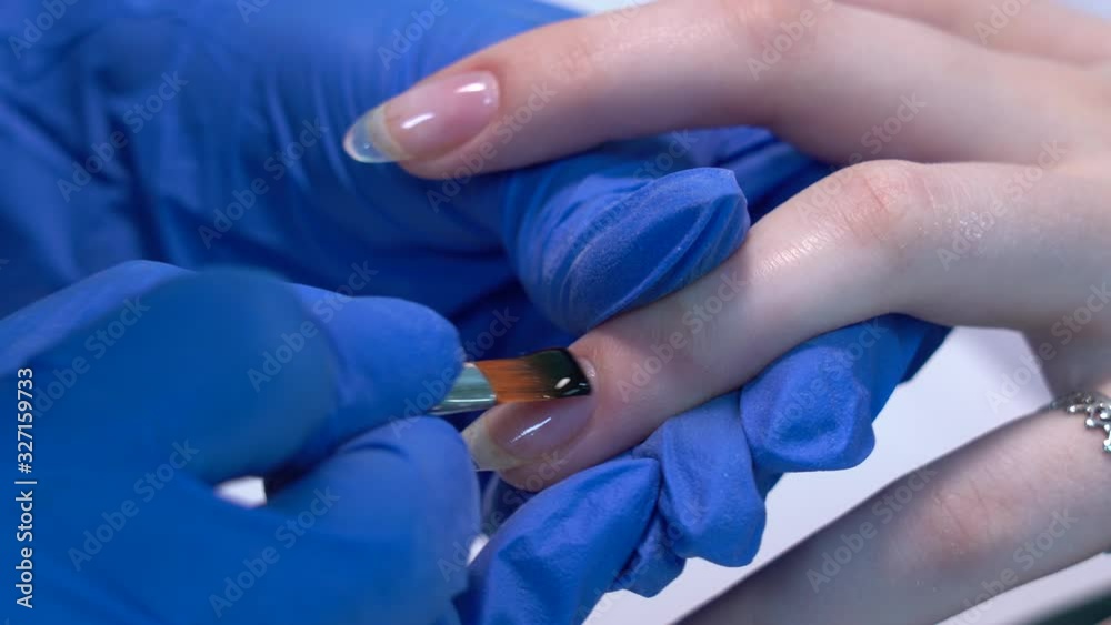 Closeup view 4k video of applying transparent nail varnish base gel coating. Professional manicurist and process of modern nails treatment in beauty salon. Closeup view 4k video of applying transparent nail varnish base gel coating. Professional manicurist and process of modern nails treatment in beauty salon.