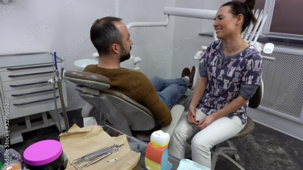 Dentist is talking to the male patient to understand the dental problem. Dental Clinic Dentist is talking to the male patient to understand the dental problem. Dental Clinic