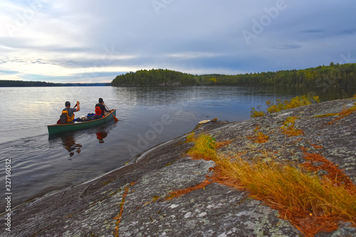 Two paddlers canoe the calm autumn waters of Cirrus Lake in Quetico Provincial Park, Ontario, Canada photo