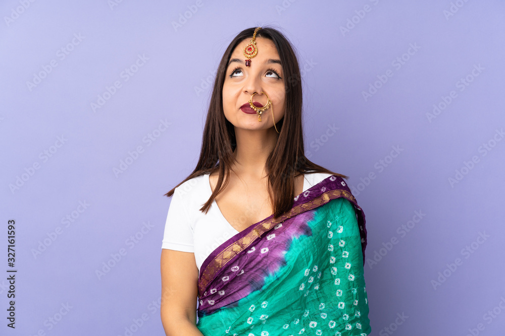 Young Indian woman isolated on purple background and looking up Young Indian woman isolated on purple background and looking up