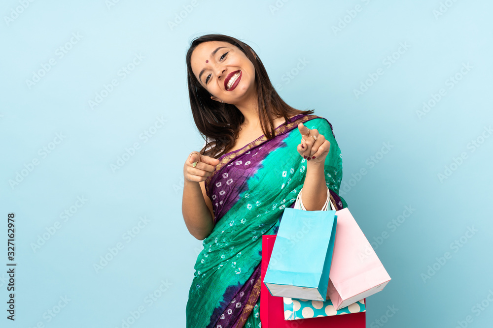 Young Indian woman with shopping bags pointing front with happy expression Young Indian woman with shopping bags pointing front with happy expression