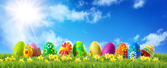 Colorful Easter eggs on green grass with spring flowers