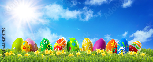 Colorful Easter eggs on green grass with spring flowers