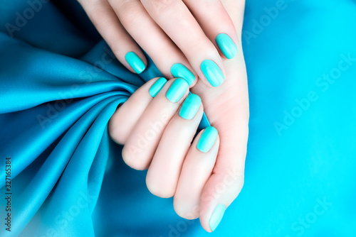 Female hands with manicure mint turquoise on a turquoise background