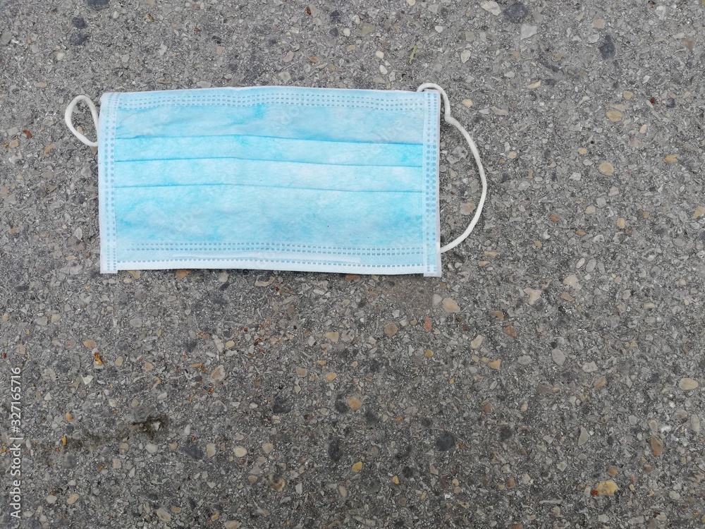 Disposable surgical mask thrown on the ground Disposable surgical mask thrown on the ground
