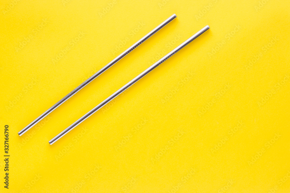 Two straight metal reusable cocktail tubes on a yellow uniform background. The concept of life without waste. Two straight metal reusable cocktail tubes on a yellow uniform background. The concept of life without waste.