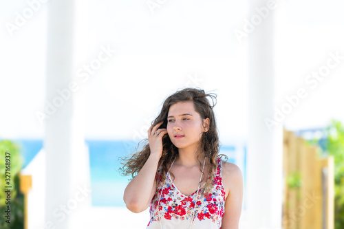 Seaside pavilion by gulf of mexico ocean with water and happy young woman girl touching hair in Florida architecture view during sunny day Free Download Seaside pavilion by gulf of mexico ocean with water and happy young woman girl touching hair in Florida architecture view during sunny day - GFXLoad