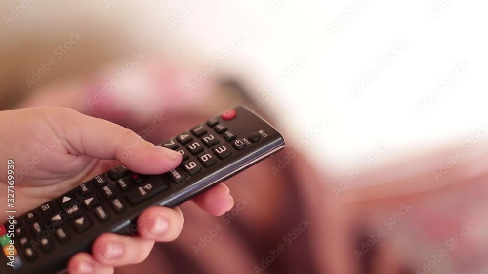 The TV remote in the hand of the girl which switches channels. The TV remote in the hand of the girl which switches channels.