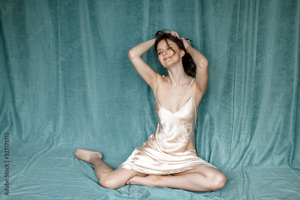 happy brunette woman sitting on a green background in a dress. happy brunette woman sitting on a green background in a dress.