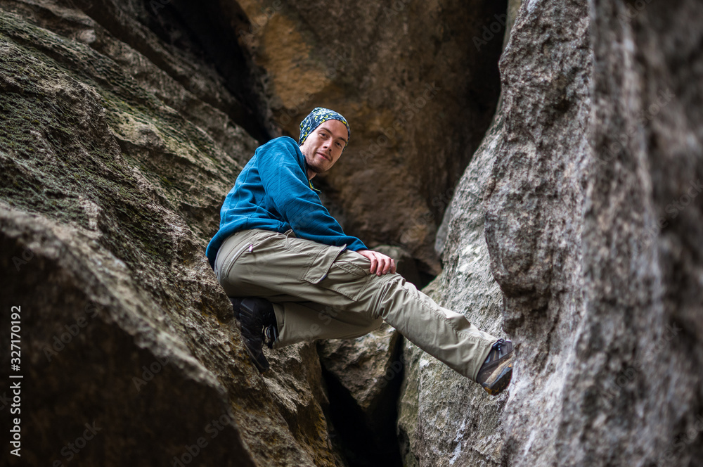 Tourist in blue jacket sitting in a crevice among the rocks.