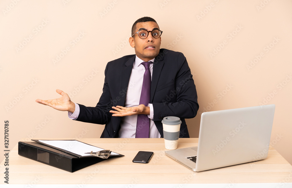Young business man in his office with a laptop and other documents with surprise facial expression Young business man in his office with a laptop and other documents with surprise facial expression