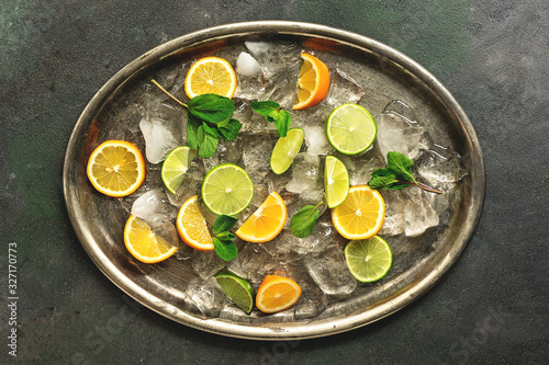 Lime and lemon slices  mint leaves and crushed ice on a metal rustic tray. Top view  flat lay. Ingredients for a cocktail.