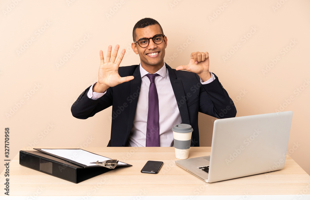 Young business man in his office with a laptop and other documents counting six with fingers Young business man in his office with a laptop and other documents counting six with fingers