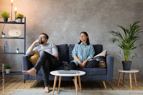 Young Couple Sitting on the Sofa. The Woman Tears Up The Photo. Family Conflict.