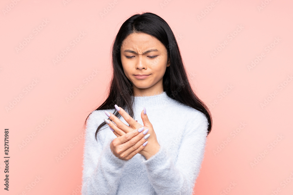 Teenager Chinese woman isolated on pink background suffering from pain in hands Teenager Chinese woman isolated on pink background suffering from pain in hands