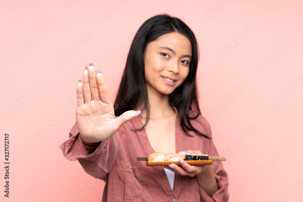 Teenager Asian girl eating sushi isolated on pink background applauding Teenager Asian girl eating sushi isolated on pink background applauding