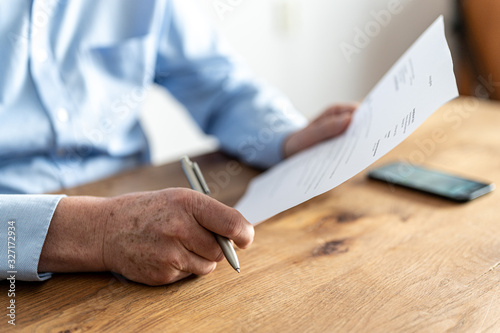 Elderly man reading a letter from the tax authorities. photo