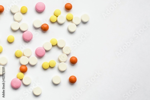 The concept of pills for treatment. Multi-colored white, orange, yellow, pink tablets on a white isolate background . Copy space. Place for text.
