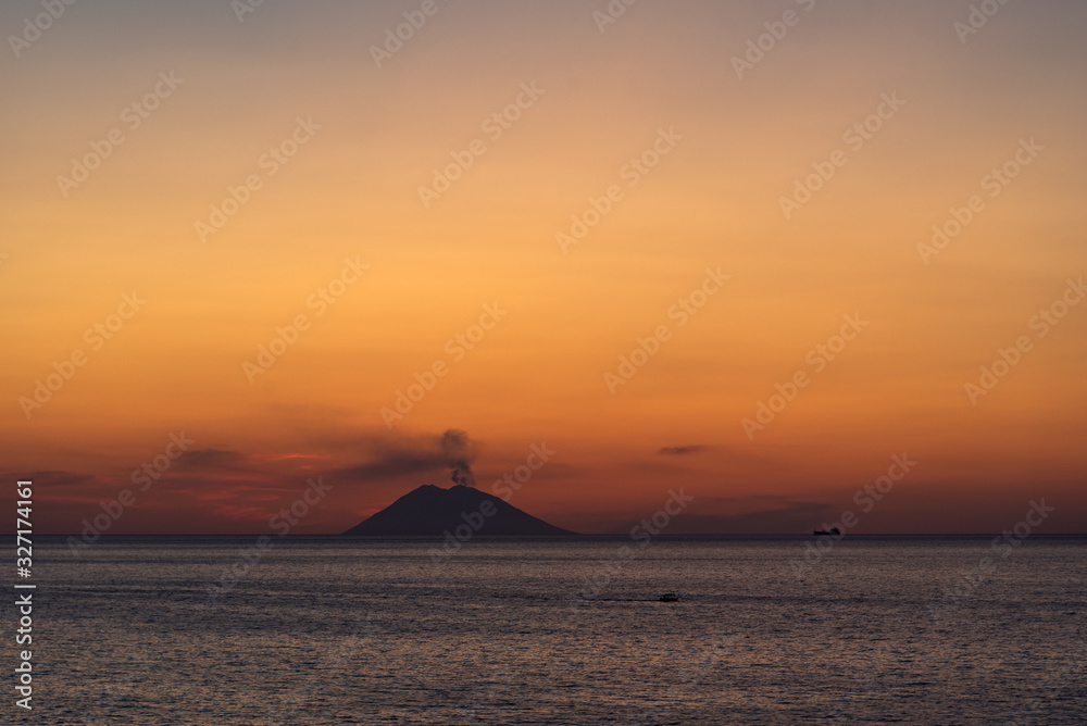 Volcano Stromboli smoking in the sunset.