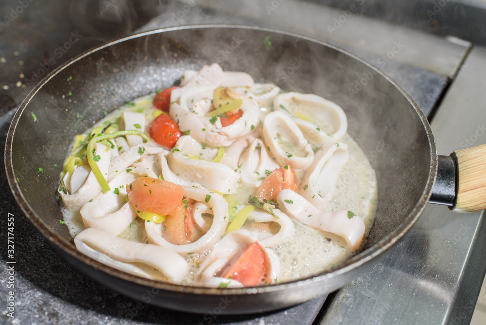 Frying pan with freshly cooked squid in white wine. Tasty and healthy food. Frying pan with freshly cooked squid in white wine. Tasty and healthy food.