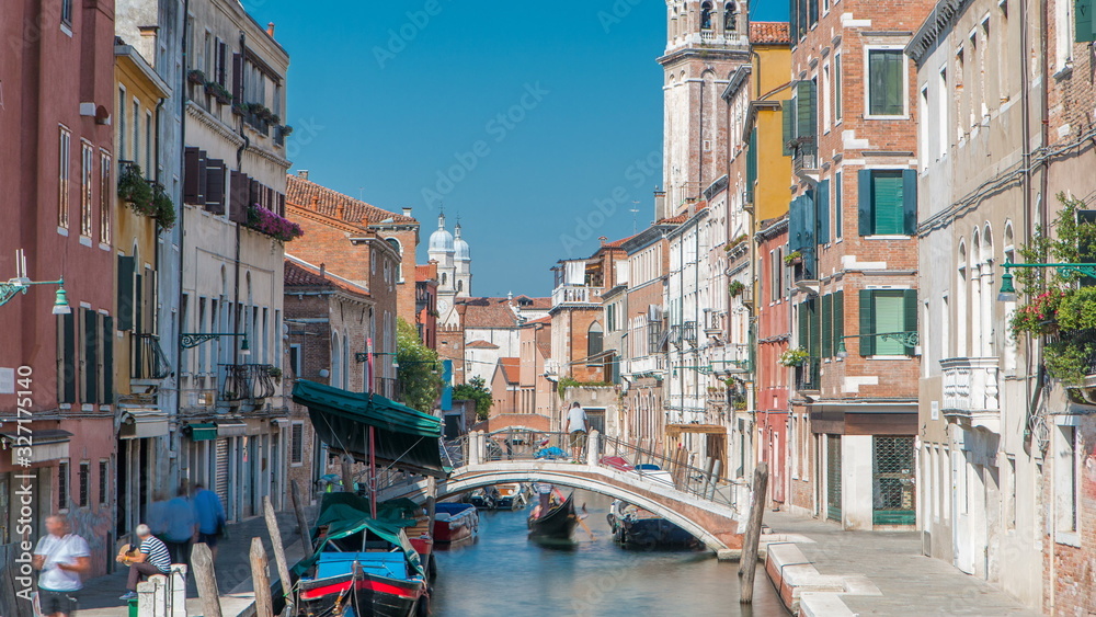 A view of Venice timelapse: canal, bridge, boats and an old tower in the background