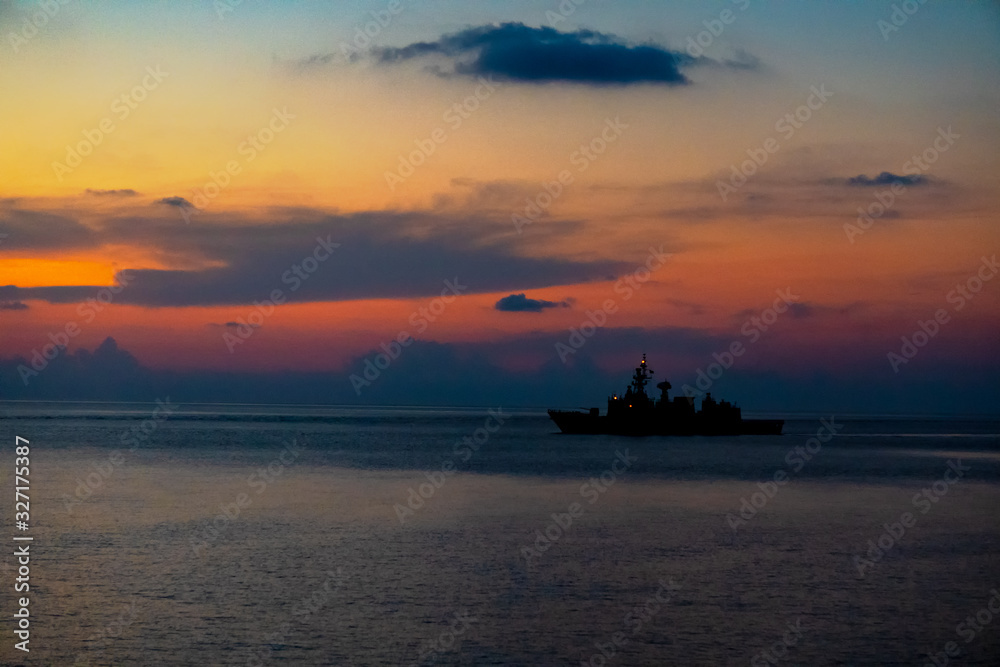Silhouette of warship sails in the sea when the red light of civil twillight brace upon the sea surface. Silhouette of warship sails in the sea when the red light of civil twillight brace upon the sea surface.