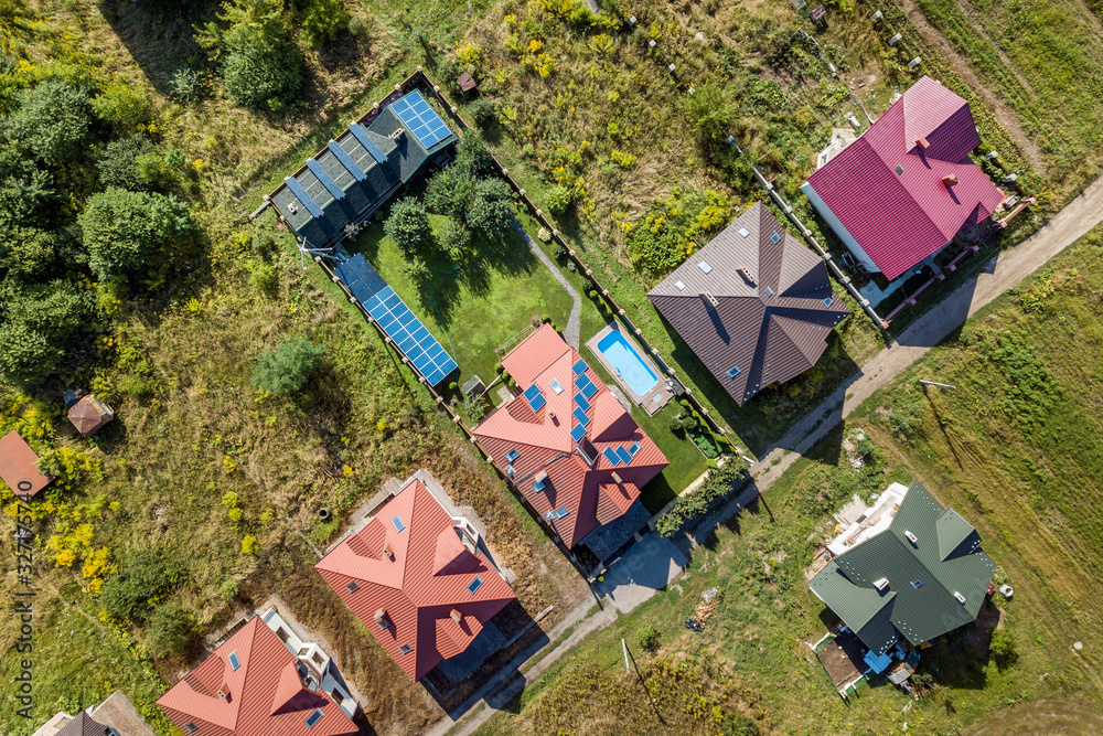 Fototapeta premium Aerial view of rural residential area with private homes between green fields.