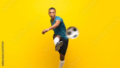 Fototapeta Naklejka Na Ścianę i Meble -  Afro American football player man over isolated yellow background