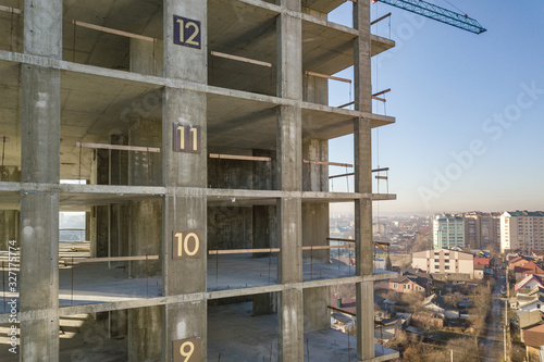 Aerial view of concrete frame of tall apartment building under construction in a city. © bilanol