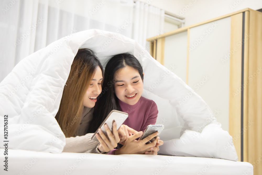 Asian Girl Using Smartphone on Bed Before Sleeping. Mobile Addict Concept. Happy Woman Holding Mobile Phone. Sleepy Woman.technology and people concept .Young woman sleeping in bed at home at night.