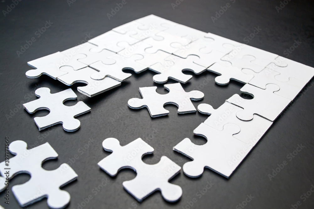 Obraz premium White puzzles on a black background close-up