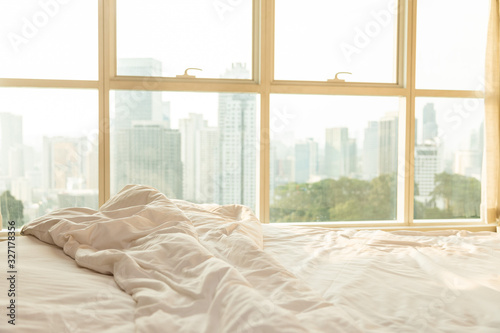morning bed against a panoramic window, and outside the window there are skyscrapers and dawn