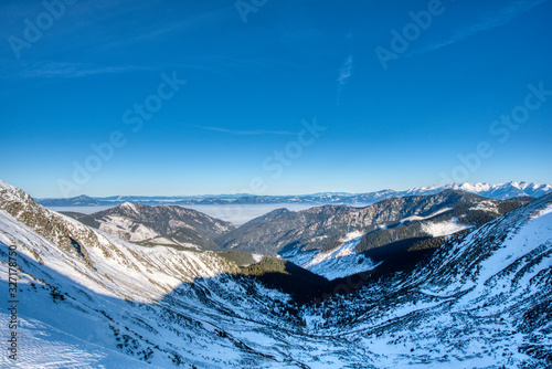 view of mountains west Tatra mountains and valley with fog and blue sky from ridge in Low Tatras, Slovakia © Martin