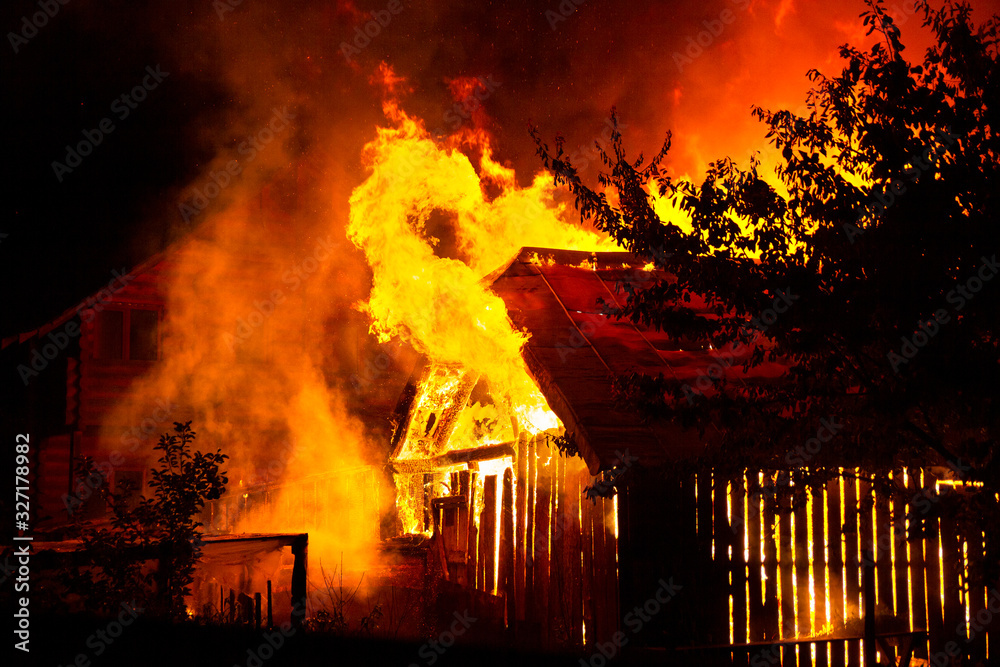 Wooden house or barn burning on fire at night.