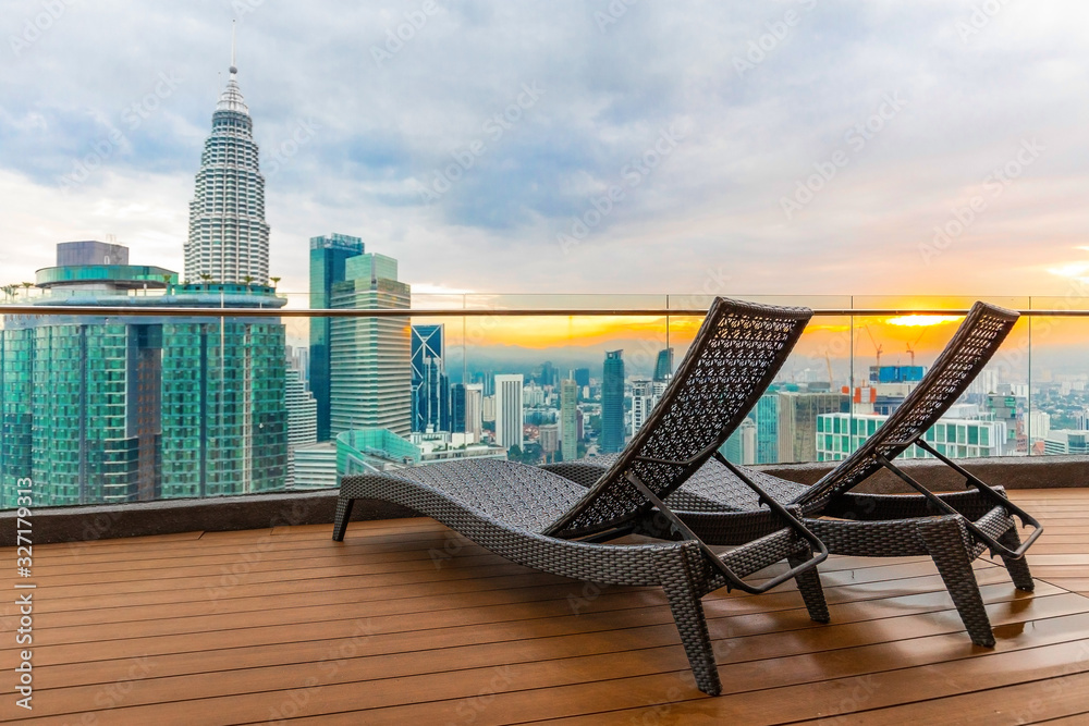 Naklejka premium Sun loungers on the roof of a skyscraper overlooking Kuala Lumpur and sunset.