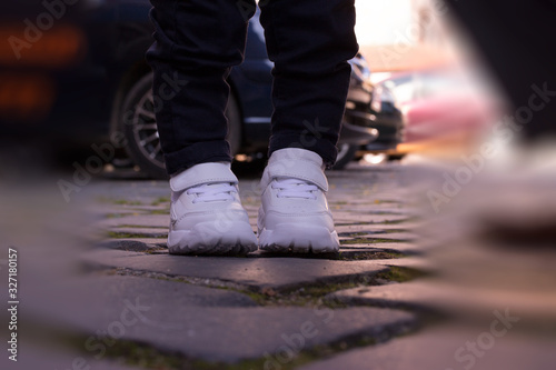 kid white sports shoes pads pavement blur jeans little legs boy standing
