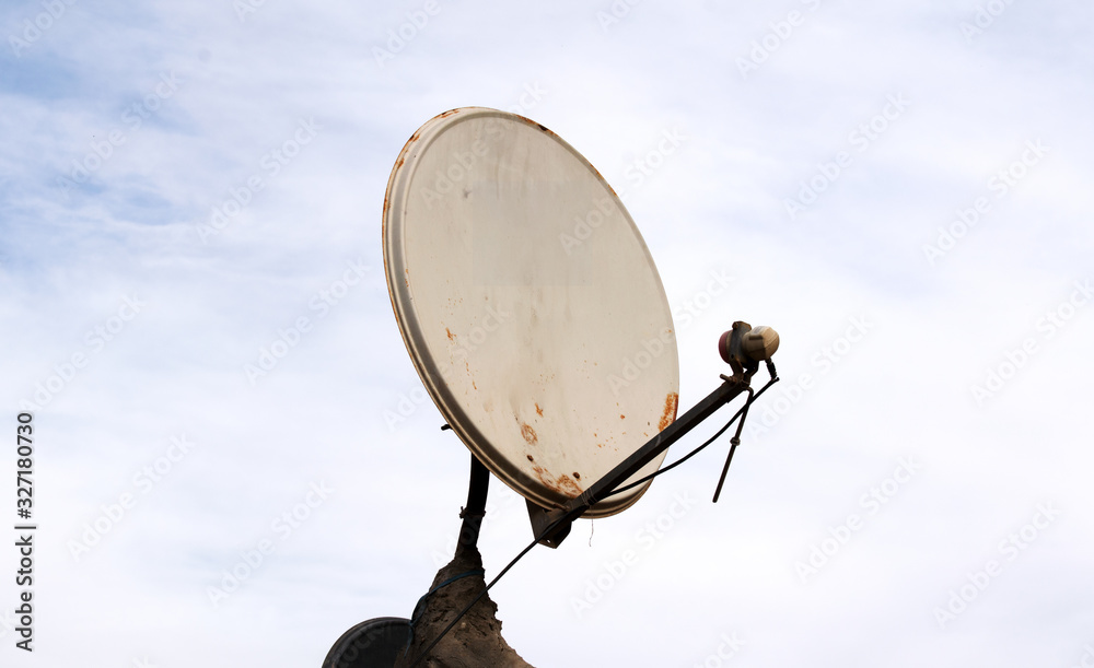 Satellite dish antenna over blue sky and roof background Satellite dish antenna over blue sky and roof background