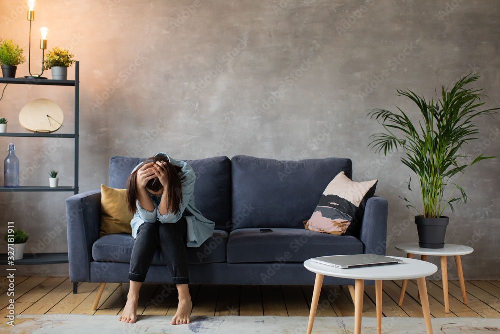 Worried woman sitting on couch at home. Frustrated confused female ...