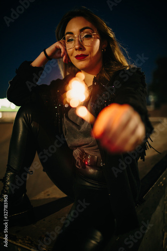 Young blonde girl with glasses plays at night with a fireworks candle photo