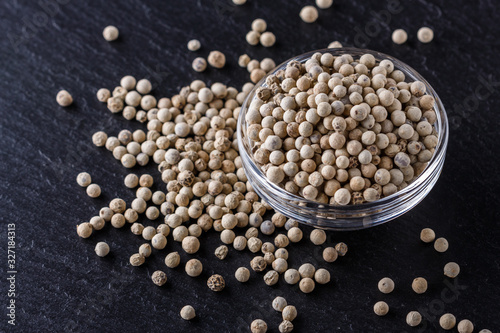 white peppercorns in glass bowl on stone background