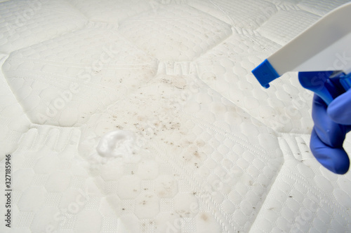 Mattress cleaner spray. Cleaning a mattress cloth with a foam stain remover. Hand pulls a trigger.
